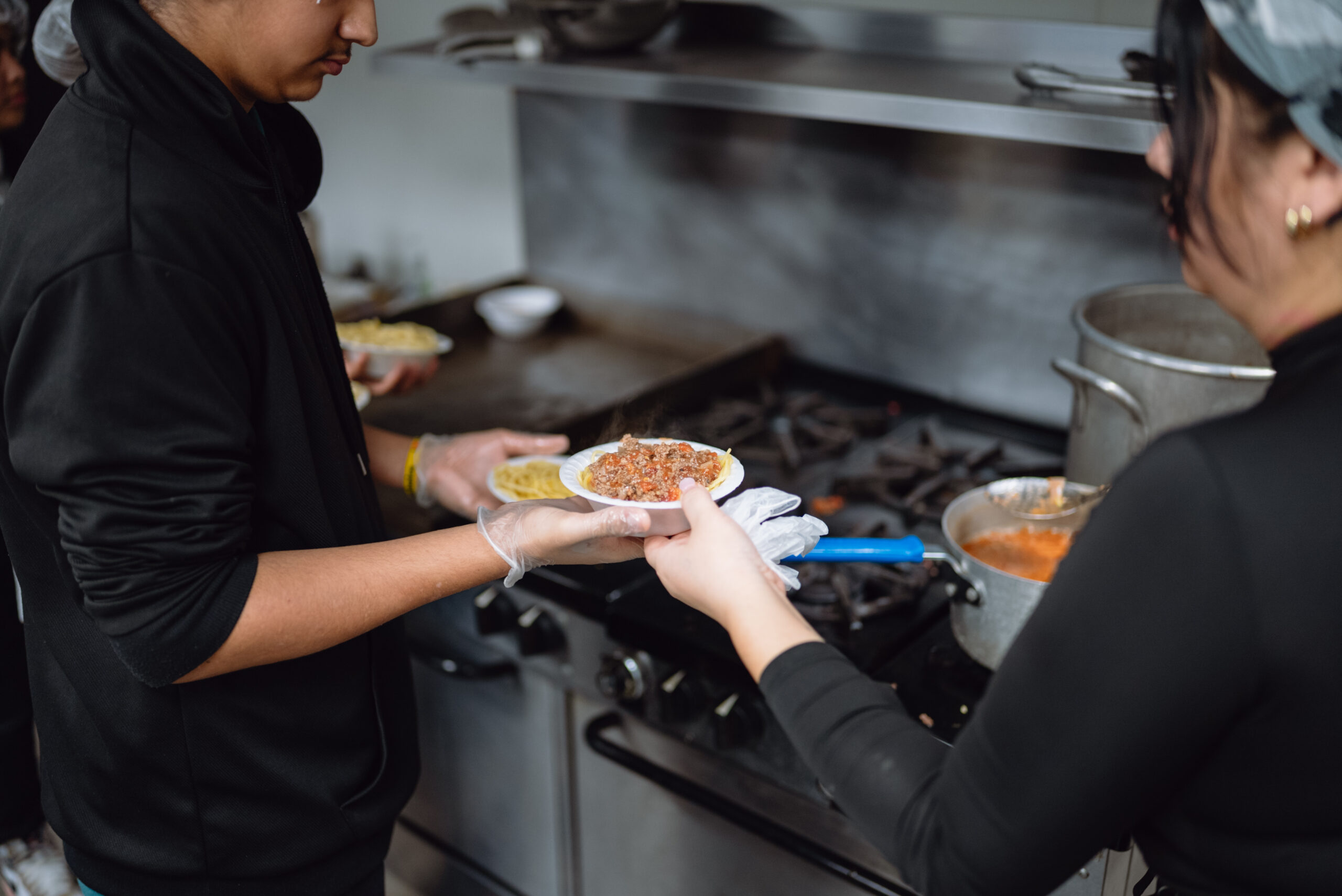 person passing off food at a kitchen